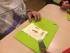 Na zdjęciu znajduje się chłopiec przygotowujący ciastko.